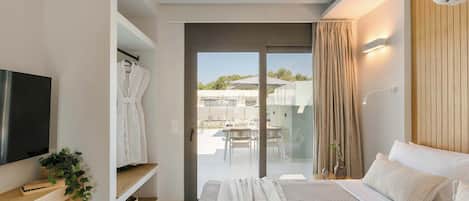 Een moderne slaapkamer met een groot bed, een televisie, een kledingkast en een schuifdeur naar een balkon.