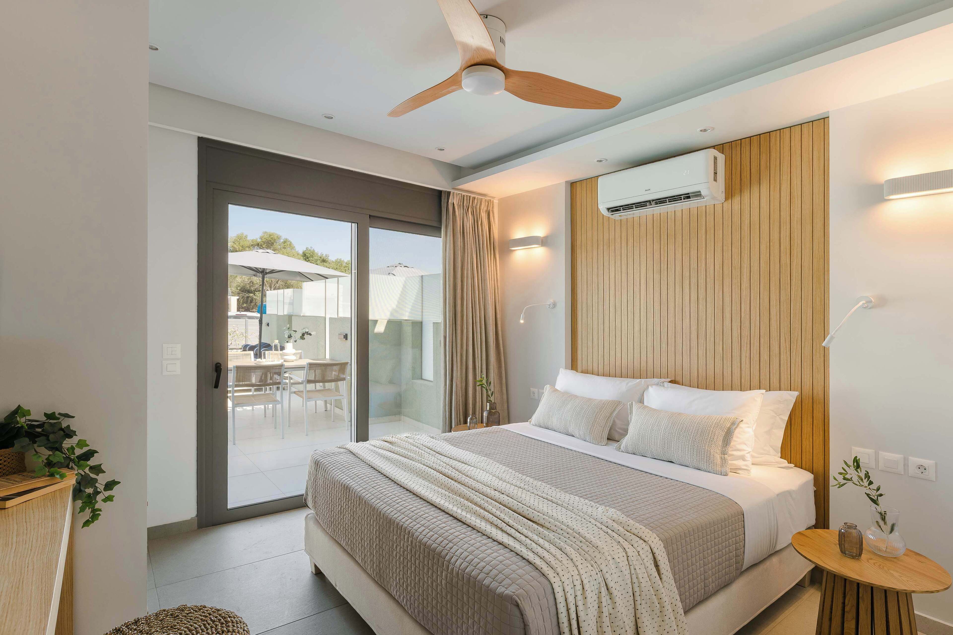 Un dormitorio moderno con cama, ventilador de techo y equipo de aire acondicionado.