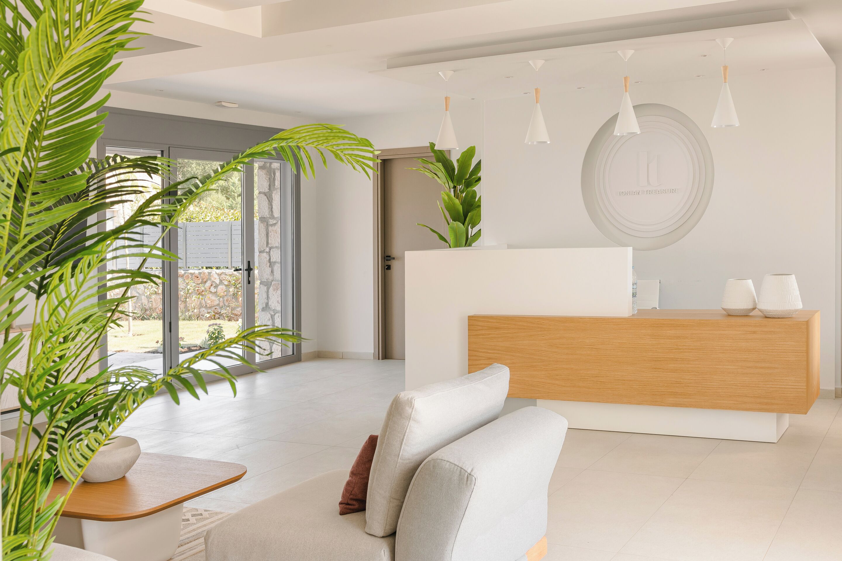 A modern reception area with a wooden reception desk, a white sofa, and potted plants.