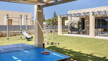 Una mesa de ping pong al aire libre con red, rodeada por una estructura de pérgola.