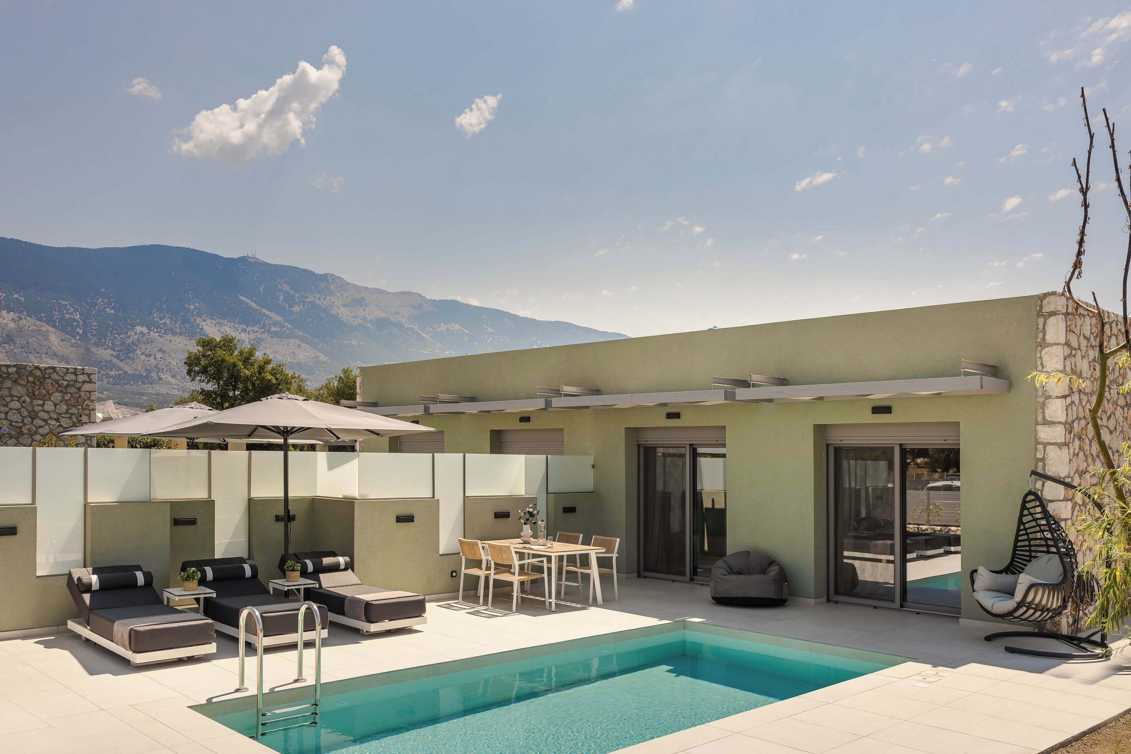 A modern outdoor pool area with lounge chairs, a table, and umbrellas.