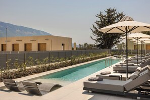 A poolside area with lounge chairs, umbrellas, and a pool. - Ionian Treasure Suites (Kefalonia)