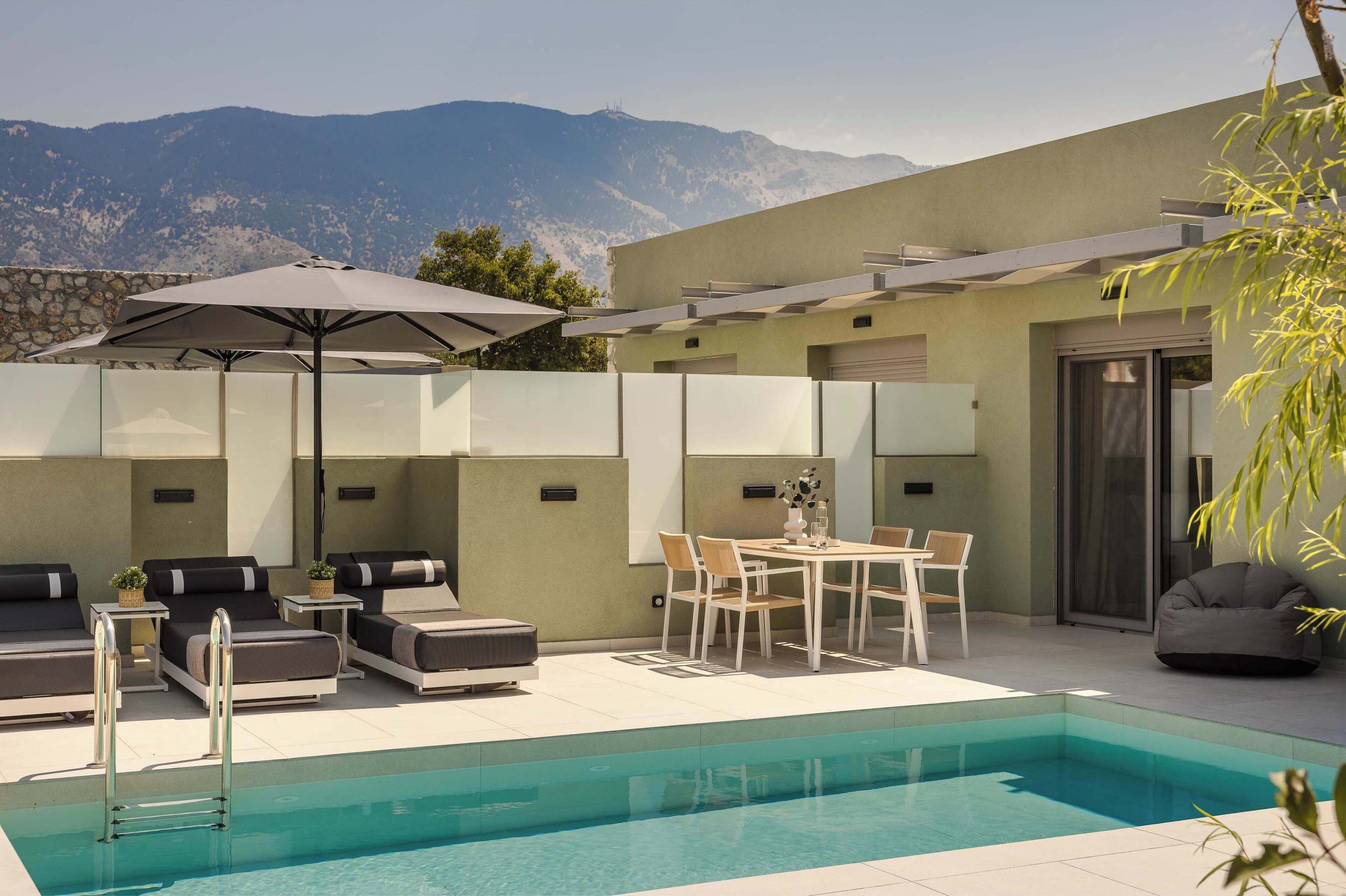 A modern outdoor pool area with lounge seating, a table, and a pergola providing shade.