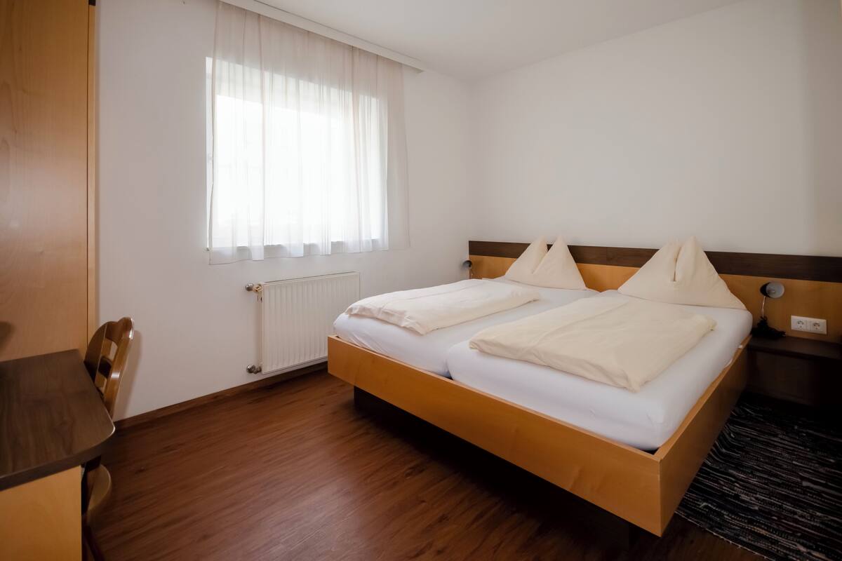 A hotel room with a wooden bed, a desk, and a chair.