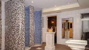 A bathroom with mosaic tile walls, a white pedestal, and a sink. - Familienhotel Steindl (Millstatt)