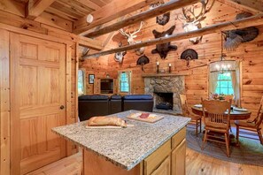 A log cabin interior with a stone fireplace, wooden walls, and antler decorations. - Cozy Log Cabin for an Ohio Outdoor Adventure near Hocking Hills State Park (New Plymouth)