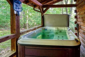 Uma banheira de hidromassagem em uma cabana de madeira com vista para uma floresta.