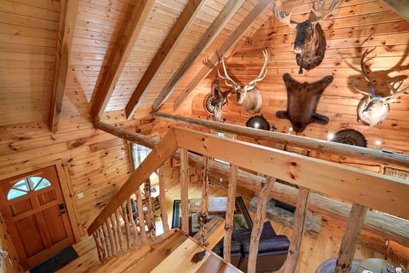 A wooden interior with a staircase, a door, and mounted animal heads.
