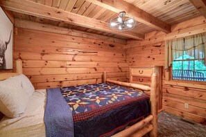 A wooden cabin bedroom with a bed, a dresser, and a window. - Cozy Log Cabin for an Ohio Outdoor Adventure near Hocking Hills State Park (New Plymouth)