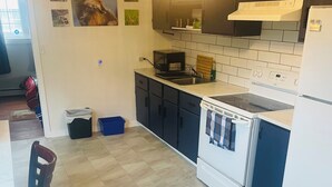 Eine Küche mit Herd, Spüle und Schränken. Im Essbereich stehen Stühle und ein Tisch.