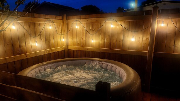 Ein Whirlpool, umgeben von einer Holzterrasse mit Lichterketten.