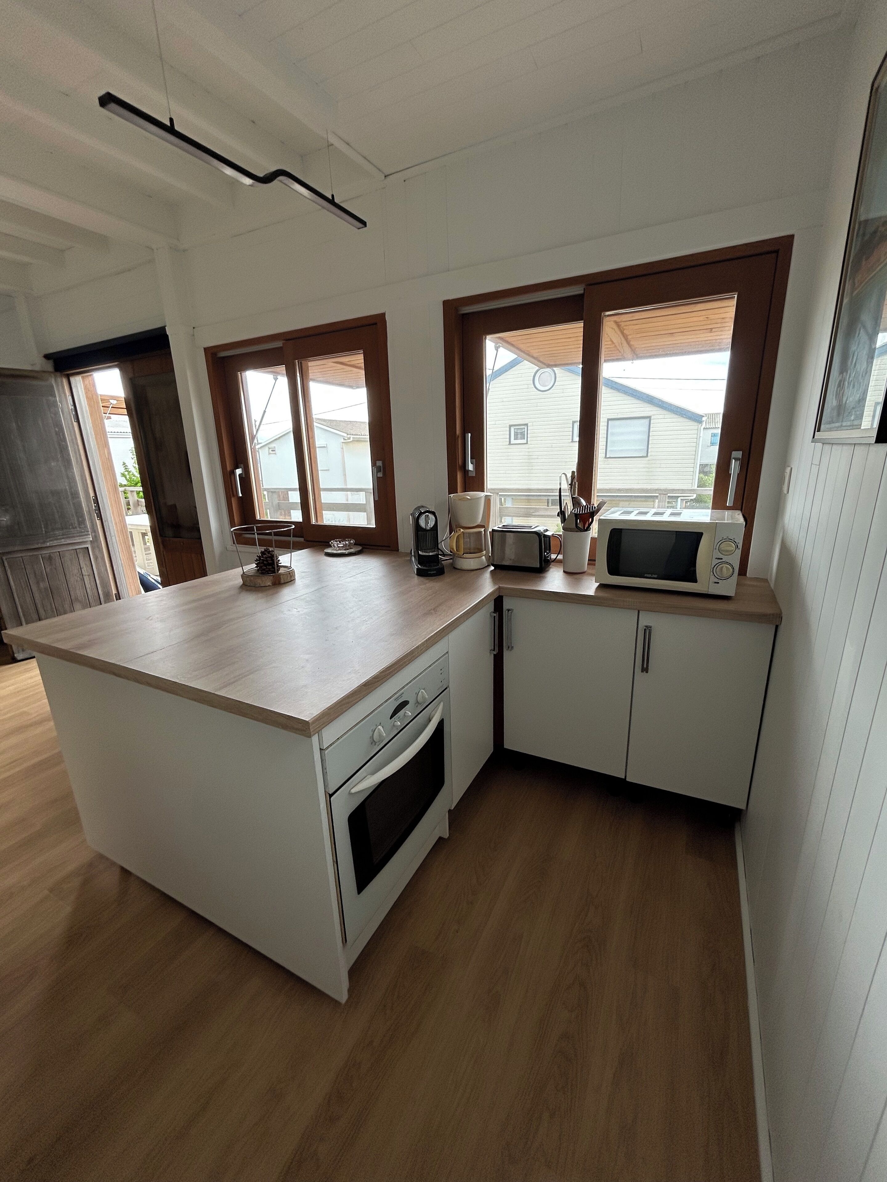 Een keuken met een centraal eiland, witte kasten en een magnetron.