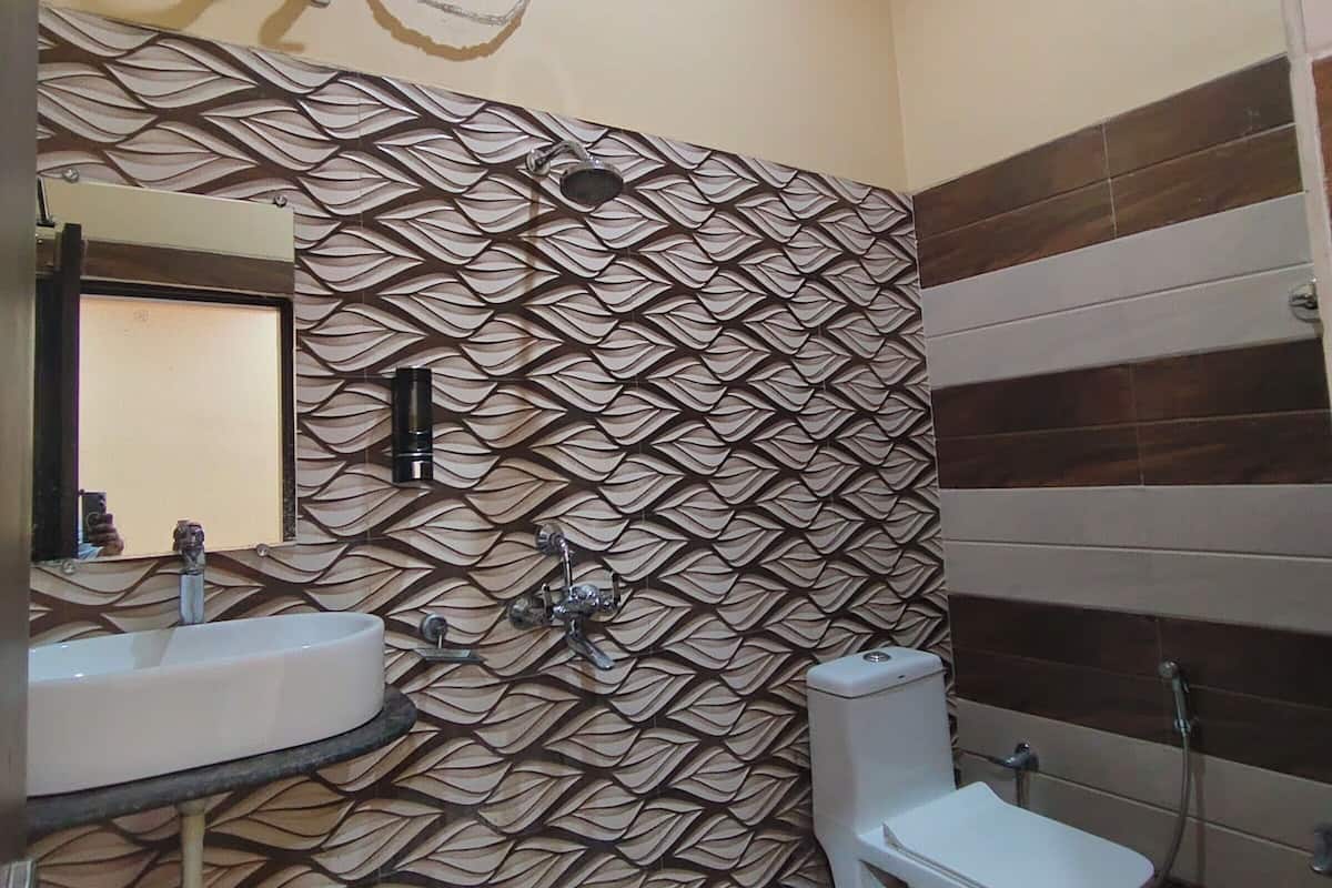A bathroom with a patterned wall, a sink, a toilet, and a hand dryer.