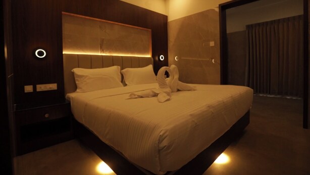 Een moderne hotelkamer met een groot bed, een houten hoofdbord en sfeervolle verlichting.