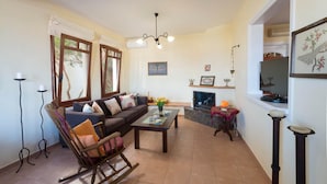 Una sala de estar con un sofá, una mecedora, una chimenea y un televisor.