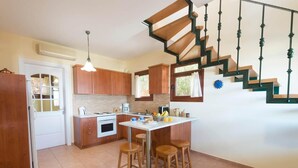 Una cocina con armarios de madera, una encimera blanca, una estufa y una zona de comedor con taburetes.