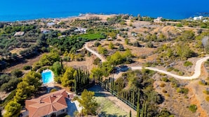 An aerial view of a coastal property with a swimming pool, terraced houses, and a clear view of the sea. - Villa Sea Pines in Nea Dimmata (Nea Dimmata)