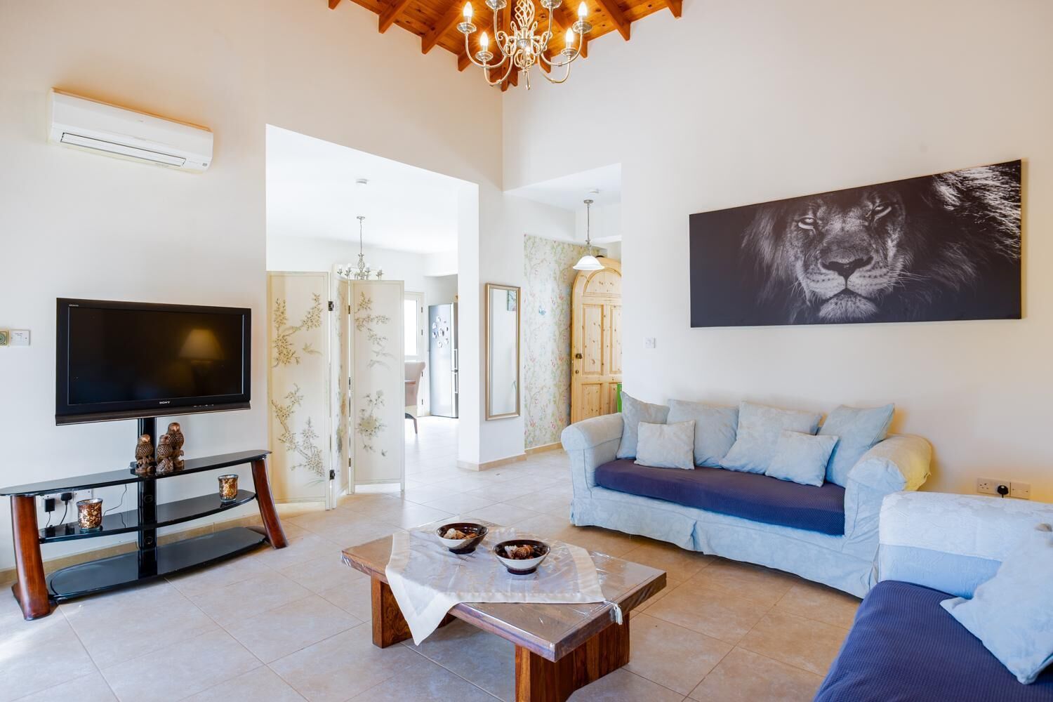 A living room with a TV, sofa, coffee table, and artwork.