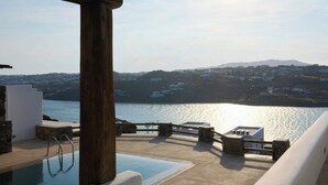 A poolside area with a view of the sea and hills. - Aegean Scent  (Mykonos)