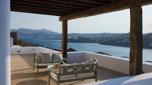 A covered outdoor seating area with a view of the sea and mountains. - Aegean Scent  (Mykonos)
