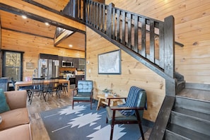 Interior acogedor de una cabaña con una escalera de madera, un comedor y una cocina.