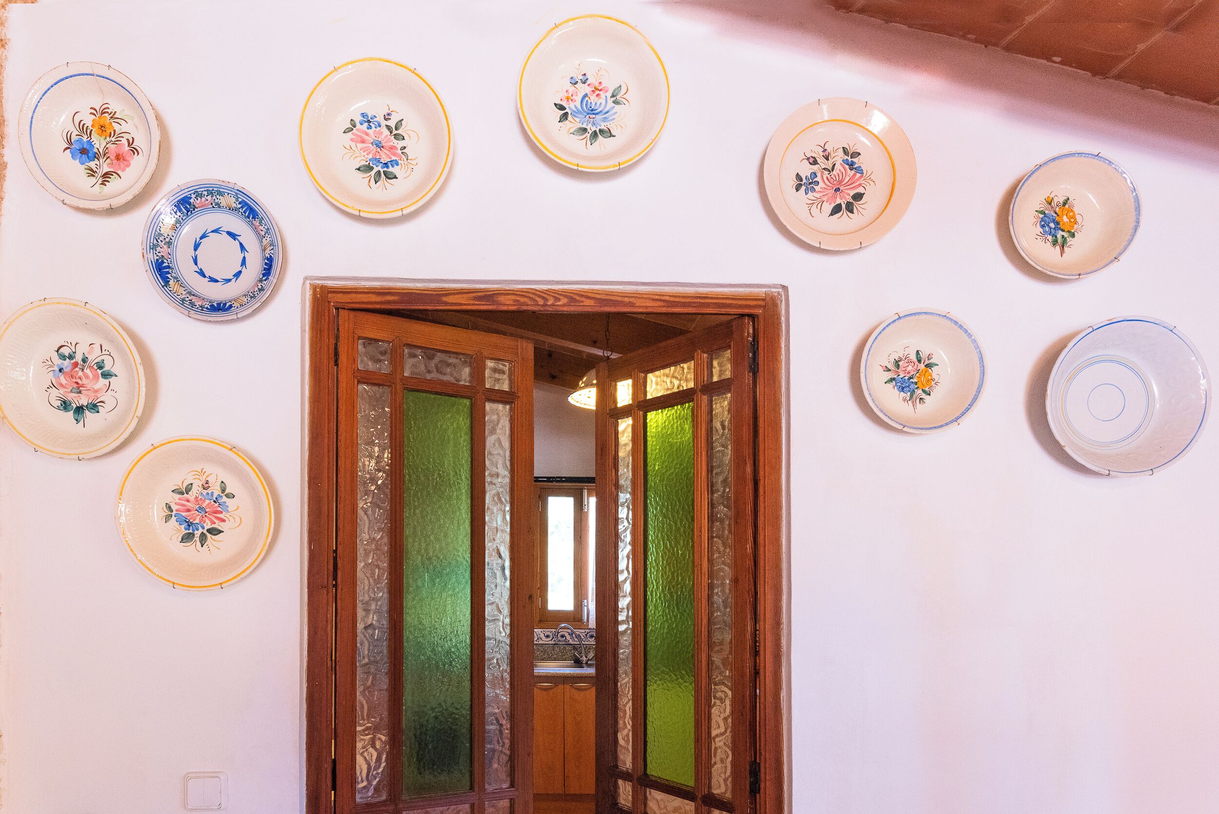 A hallway with a wooden door and a wall adorned with various decorative plates.