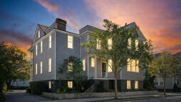 A two-story residential building with a balcony, surrounded by trees and a well-maintained lawn. - The Retreat | Downtown King 2BD w/ Porch + Parking (Charleston)