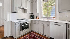 Una cocina moderna con armarios blancos, horno integrado y una ventana con persianas.