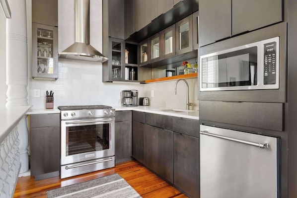 A modern kitchen with stainless steel appliances, wooden flooring, and a built-in oven.