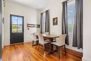 A dining area with a wooden table, six chairs, and a black door. - Historical 2bd Home w. Outdoor Space + Parking (Charleston)