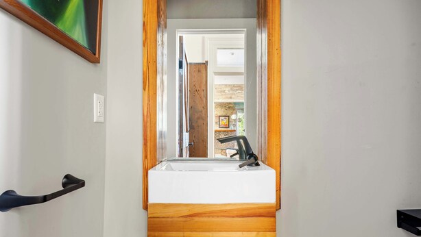 Een badkamer met een houten wastafel, een witte wasbak en een spiegel.