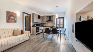A modern apartment with a living room, dining area, kitchenette, and a TV. - Secret Garda (San Felice del Benaco)