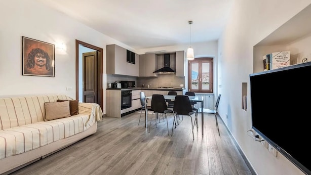 Un appartamento moderno con soggiorno, zona pranzo, angolo cottura e televisione.