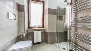 Un bagno moderno con un water, cabina doccia in vetro e portasci.