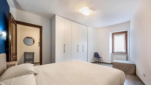 Una camera da letto con un letto, un armadio, un comodino, una sedia e una finestra.
