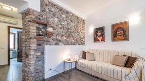 Un soggiorno con parete in pietra, un divano a righe e due opere d'arte incorniciate.