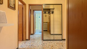 A hallway with a tiled floor, wooden doors, and a mirrored wall. - Attico Vintage Colette by Rentbeat (Verona)