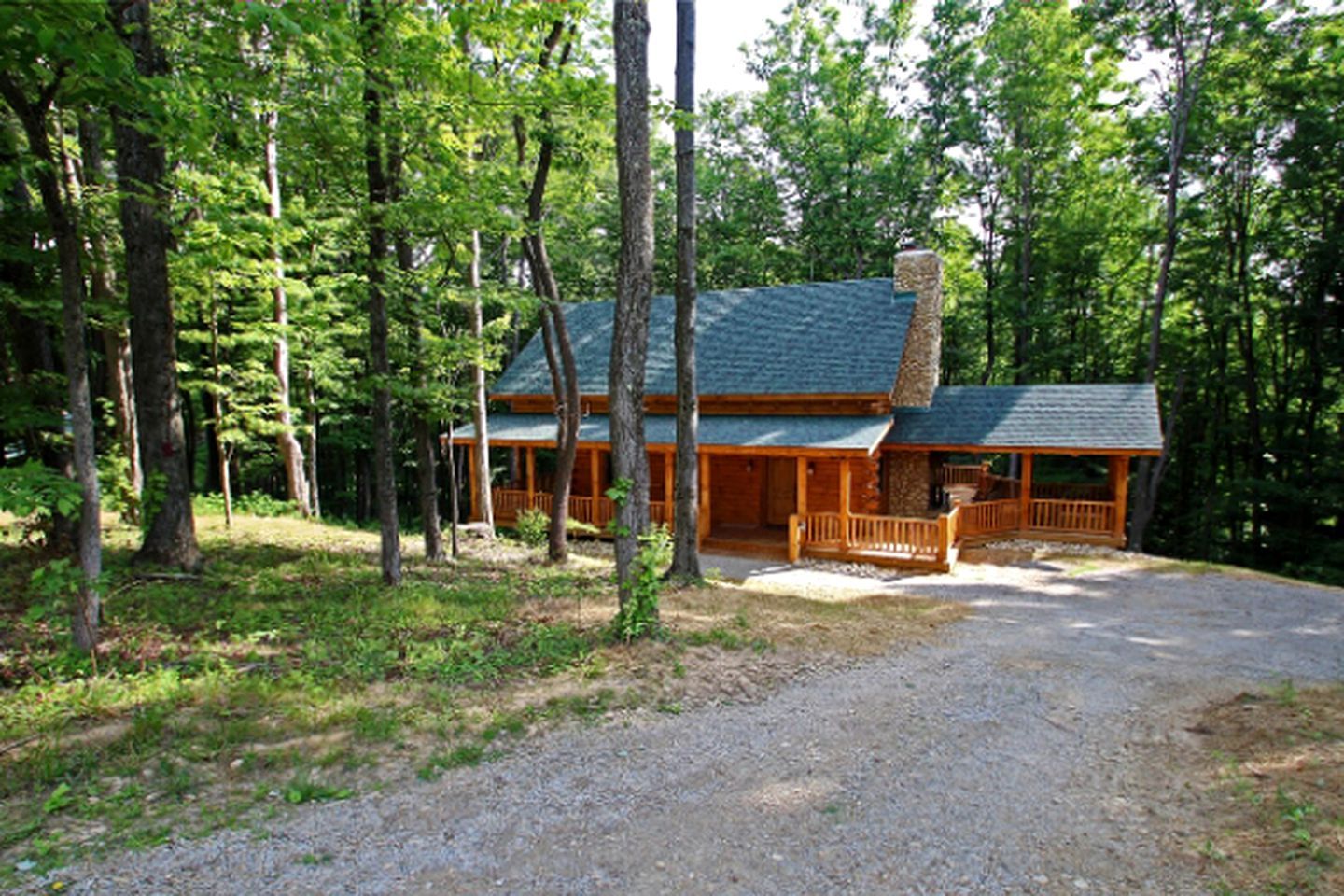 A cabin with a porch, surrounded by trees.