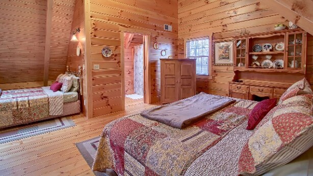 Camera in baita di legno con due letti, una cassettiera e un armadietto con soprammobili.
