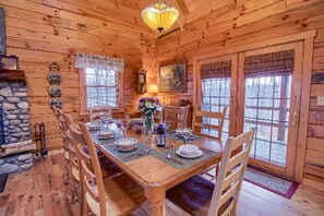 A wooden cabin with a dining table set for four, surrounded by chairs. - Secluded Log Cabin Rental with a Hot Tub in the Hocking Hills, Ohio (Logan)
