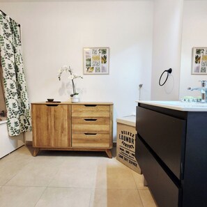 A bathroom with a wooden vanity, a black cabinet, a towel rack, and a framed botanical print on the wall. - Elegant bright apartment in Senlis (Senlis)