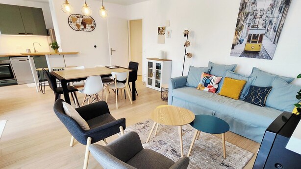 Una sala de estar moderna con un sofá, sillas, una mesa de centro y un comedor con mesa y sillas.