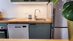 Una cocina moderna con lavavajillas incorporado, refrigerador de acero inoxidable y pileta con grifo.