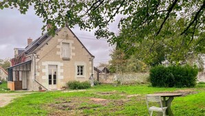 Een huis met een tuin, een bankje en een kleine tafel.