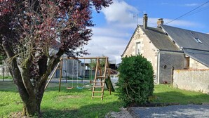Een woonwijk met een schommel, een ladder, een boom en een huis met schuin dak.