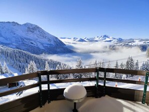A snow-covered mountain landscape with a wooden balcony and a snow globe. - Bright Apartment in Avoriaz - Perfect for Winter (Avoriaz)
