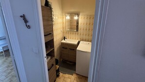Een kleine badkamer met een wastafel, spiegel en een wasmachine.