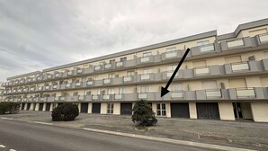 Een meerlaags woongebouw met balkons en een parkeerplaats ervoor.