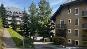 Ein Wohngebäude mit Satteldach, mehreren Balkonen und einem Weg zu einem Parkplatz.