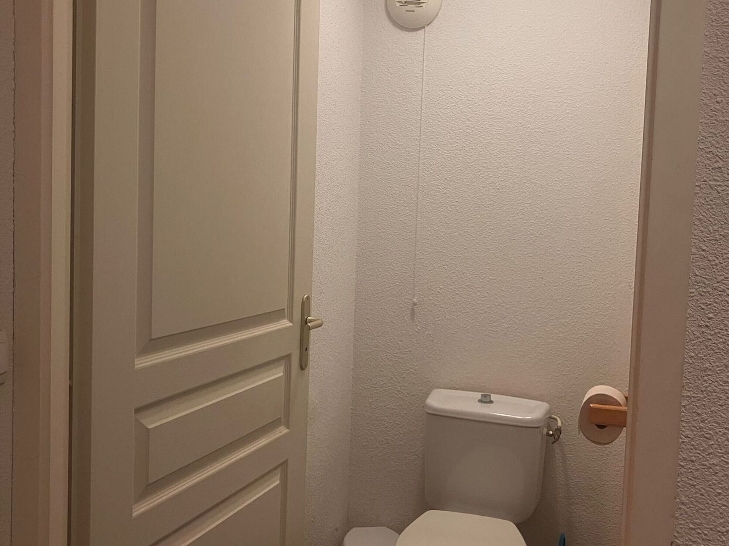A small, narrow bathroom with a white toilet and a white door.